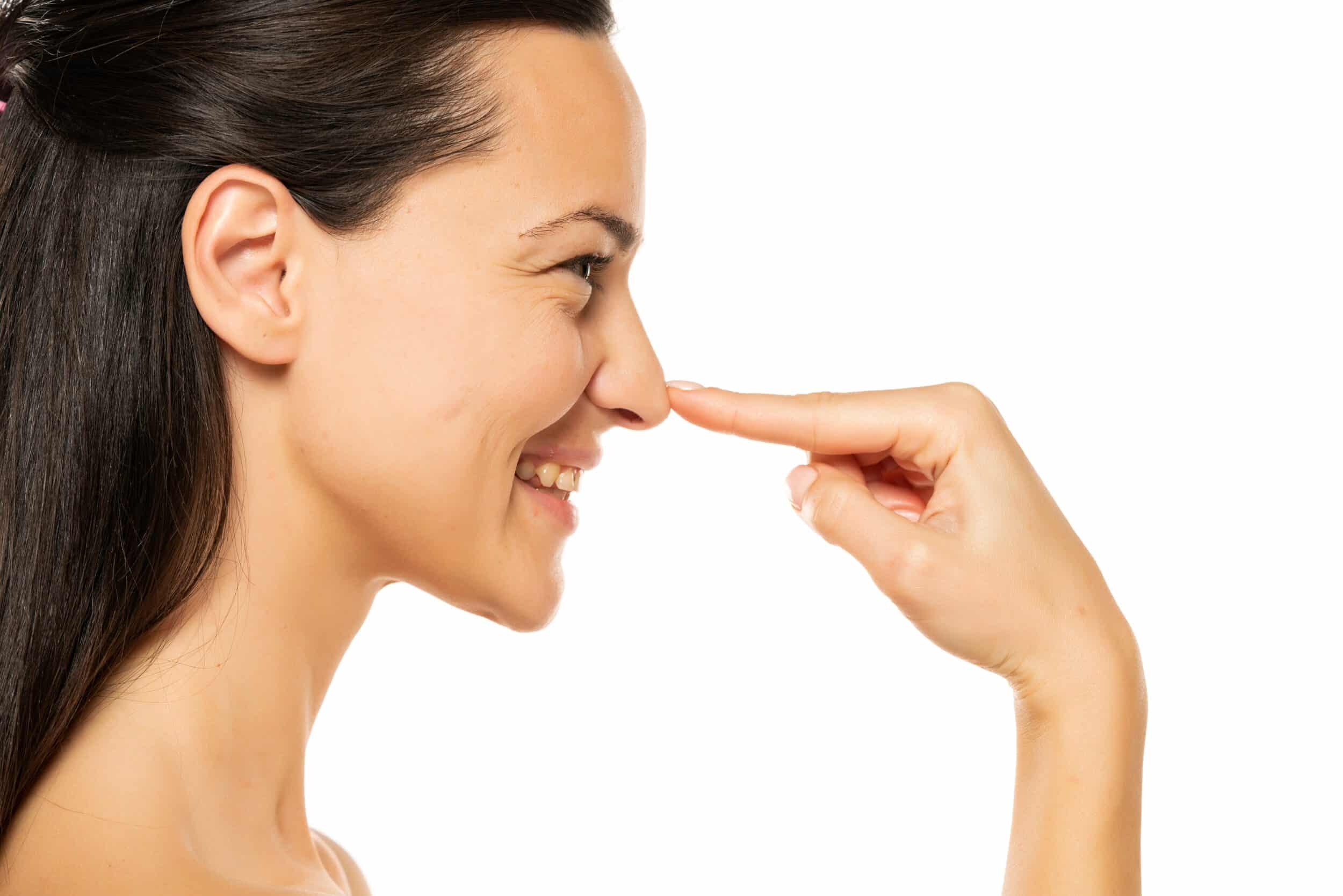A profile shot of a woman pointing to her nose after rhinoplasty in Lewisville, TX