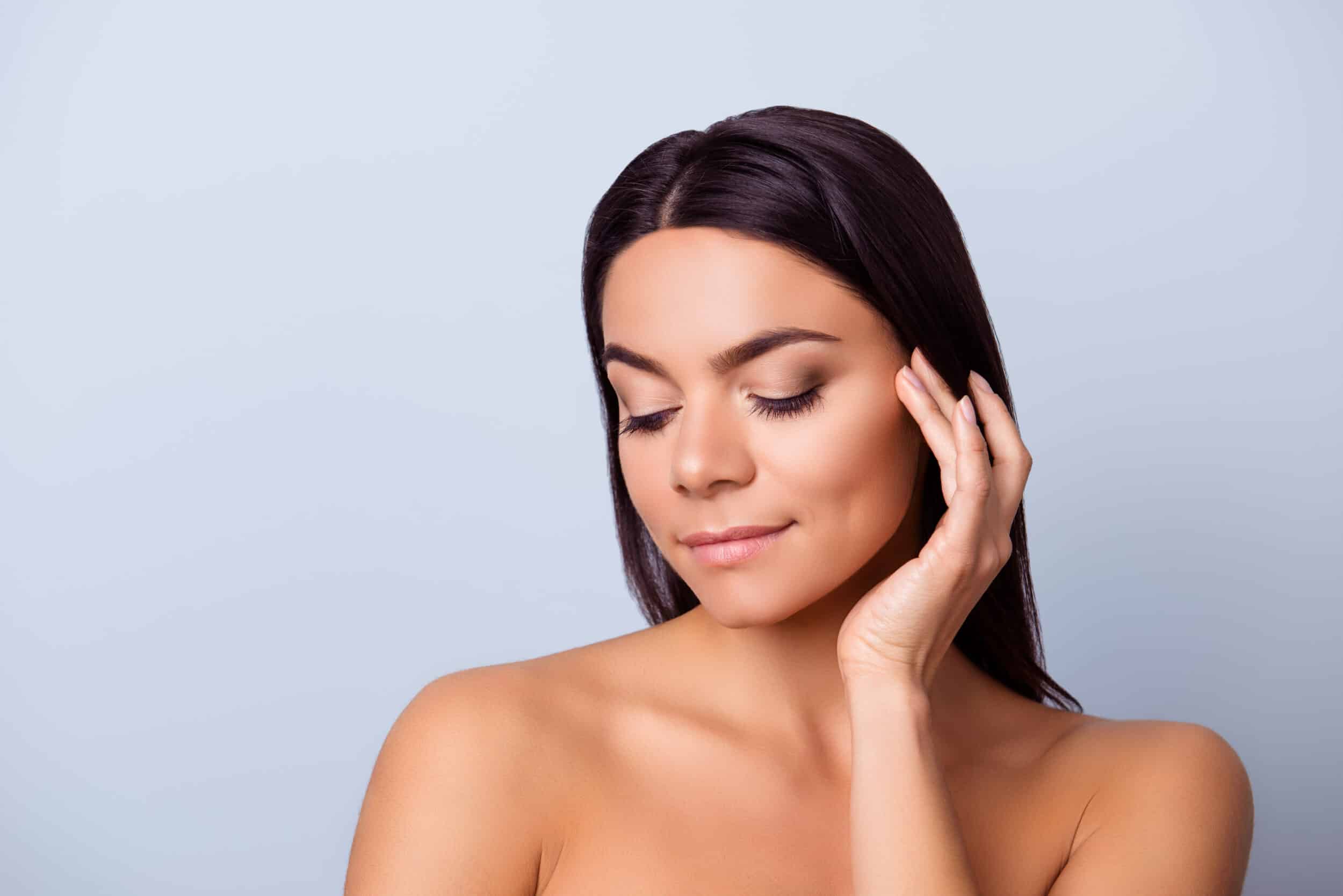 A woman touching her cheek after Sculptra® in Lewsiville, TX