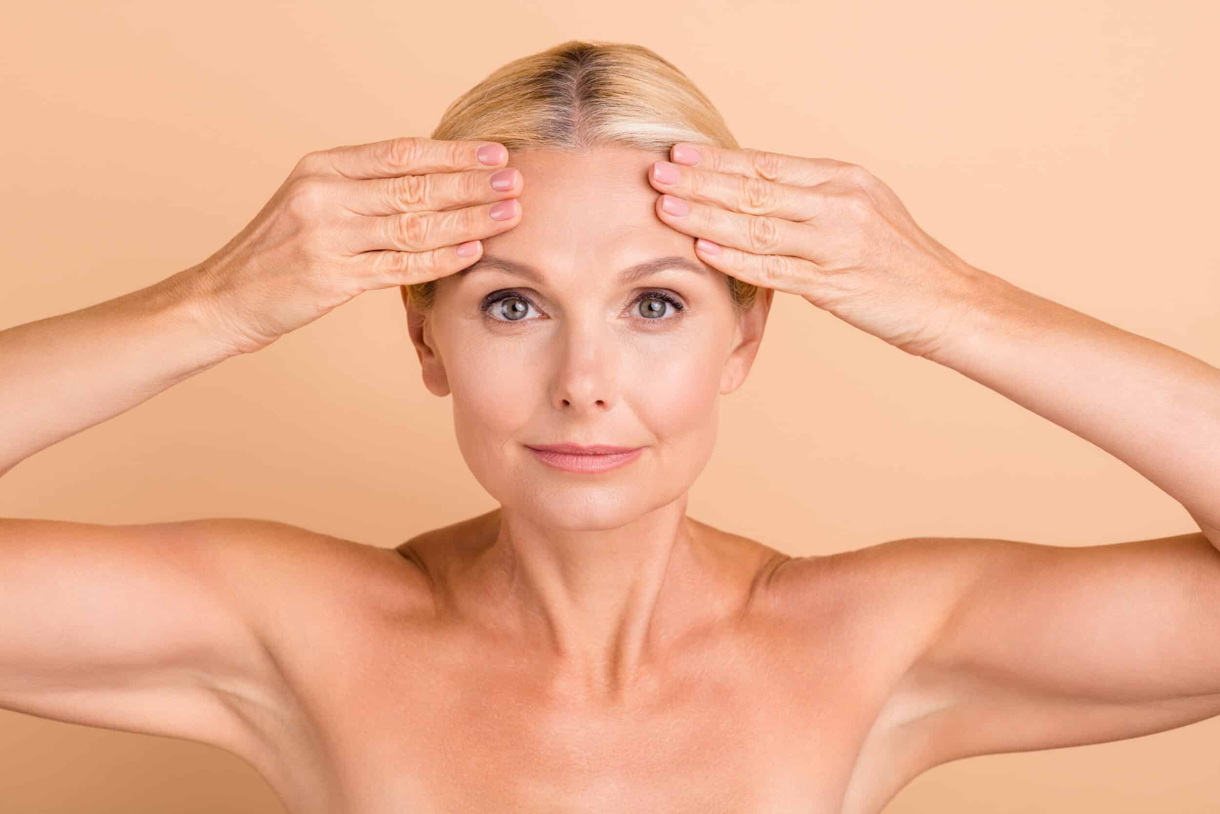 A woman touching her forehead and showing the results of a brow lift in Lewisville